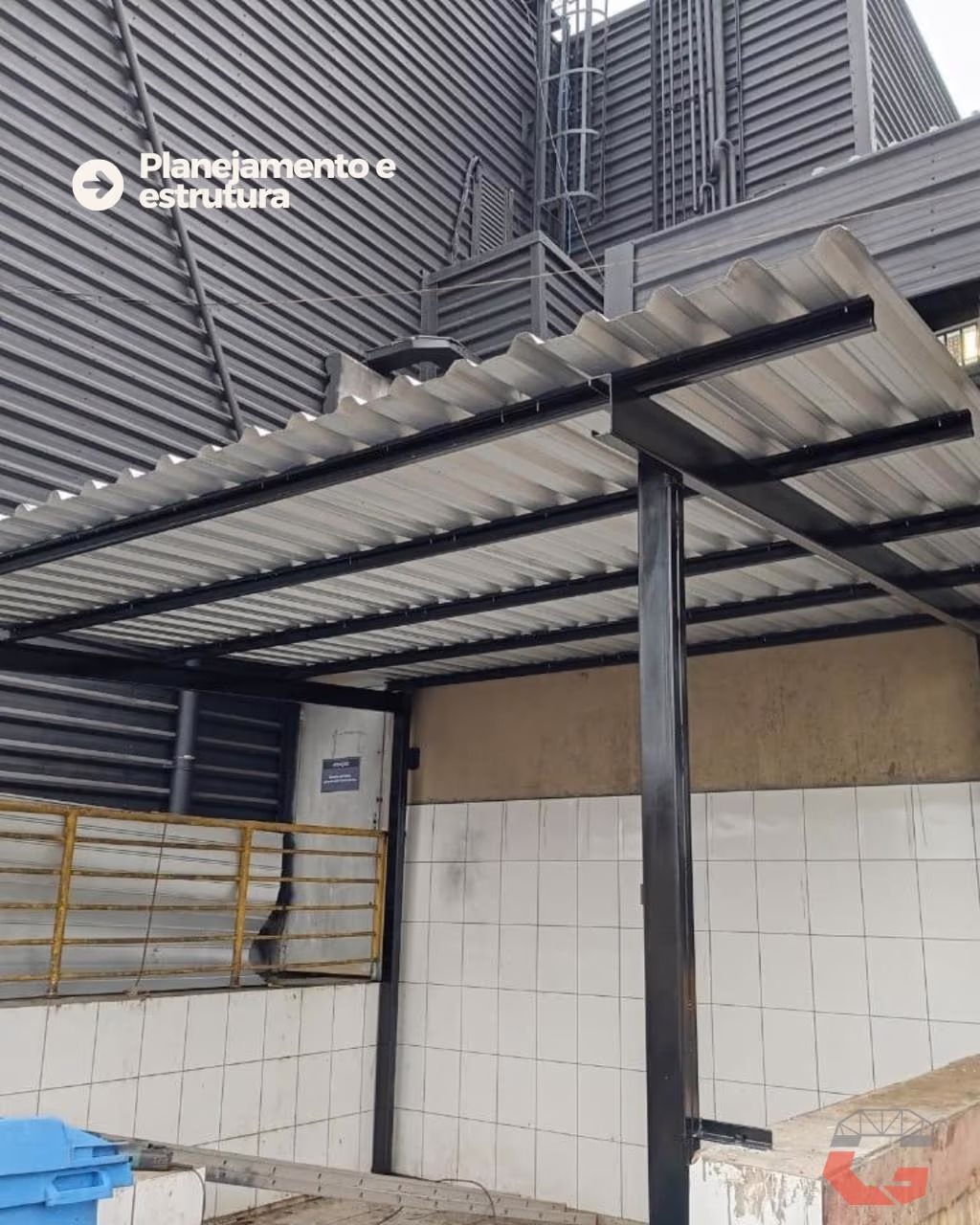 Cobertura metálica com perfis pretos e telhas metálicas sobre área de resíduos