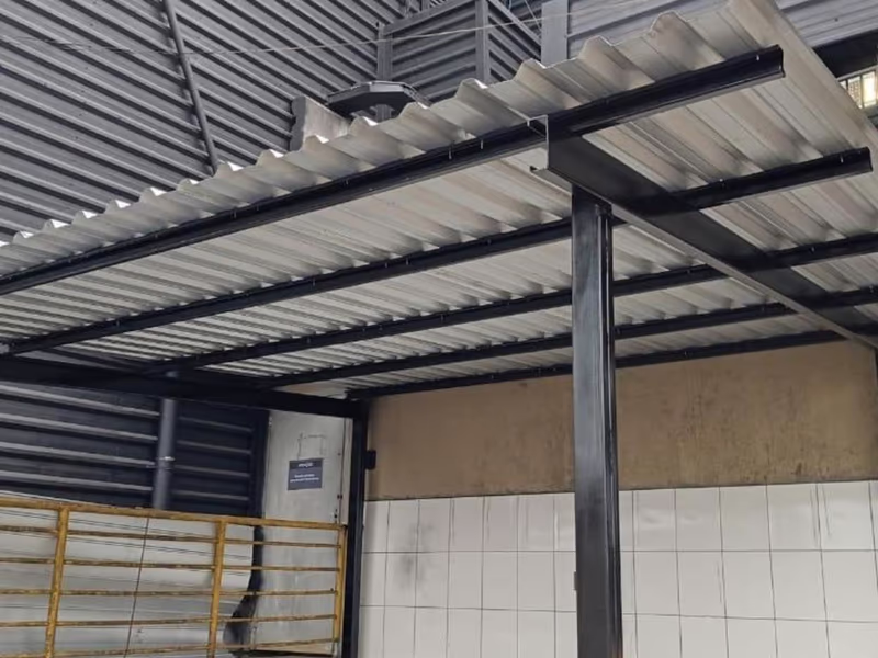 Cobertura metálica com perfis pretos e telhas metálicas sobre área de resíduos